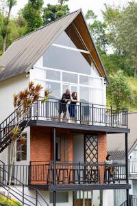 dos personas de pie en un balcón de una casa en Waterfall Villa by Opulence, en Talawakele
