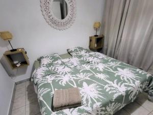 - une chambre avec un lit vert et blanc et un miroir dans l'établissement Appartement magnifique vue mer, au Gosier