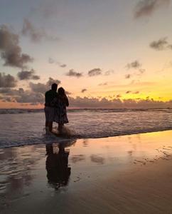 um casal de pé na praia a ver o pôr-do-sol em Baga Sea Link em Baga