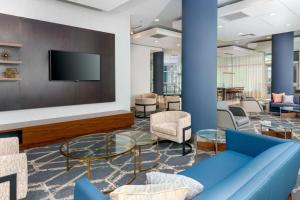 水牛城的住宿－水牛城市區/運河區萬怡酒店，大堂设有蓝色的沙发、椅子和电视。