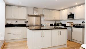 una cocina blanca con armarios y electrodomésticos blancos en Buxton Lodge en Buxton