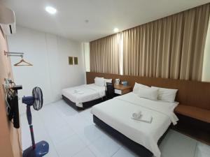 a hotel room with two beds and a desk at Hotel Wawasan in Simpang Renggam