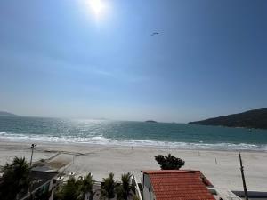 vistas a una playa con palmeras y al océano en Golfinhos Apart Hotel, en Florianópolis