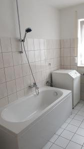 a white bath tub in a white tiled bathroom at Ferienwohnung Wippertal Biesenrode in Mansfeld +14 photos