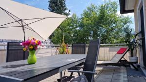 a wooden table with a vase of flowers and an umbrella at Markt 9 Appartements Oberwiesenthal in Kurort Oberwiesenthal