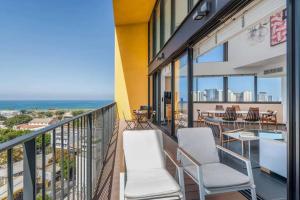 a balcony with chairs and tables and a view of the ocean at Moderne 3BR - Vue mer in Tel Aviv