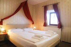 1 dormitorio con 1 cama blanca grande y toallas. en Hotel Schwarzer Adler, en Rothenburg ob der Tauber