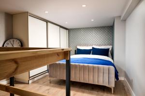 ein Schlafzimmer mit einem Bett mit blauer Bettwäsche und einer Uhr in der Unterkunft Studio z widokiem na Piotrkowską Parking in Łódź