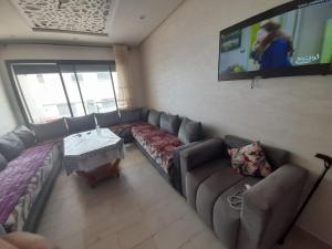 a living room with a couch and a flat screen tv at Appartement plage Mehdia in Plage de Mehdia