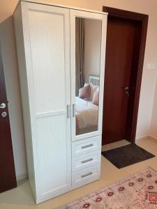 um armário branco com um espelho num quarto em One bedroom new brand in ajman em Ajman