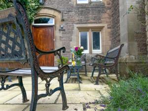 two benches sitting on a patio with a table with flowers at Geltsdale Wing, Wetheral in Wetheral