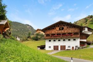 a building on a hill next to a road at Herrischner Apartement 2 in Corvara in Passiria