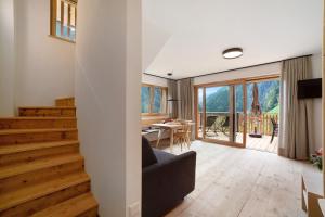 a living room with wooden stairs and a dining room at Herrischner Apartement 2 in Corvara in Passiria