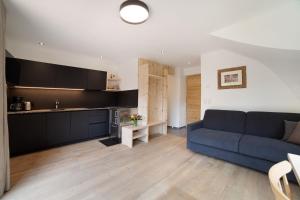 a living room with a blue couch and a kitchen at Herrischner Apartement 2 in Corvara in Passiria