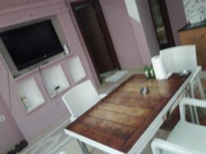 Zimmer mit einem Tisch, Stühlen und einem TV in der Unterkunft Yenifoça taş ev 1.daire in Foça