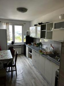 eine Küche mit weißen Schränken, einem Tisch und einem Fenster in der Unterkunft Hostel Łódźka 52 in Toruń