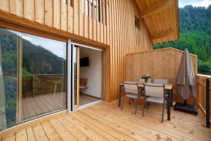 a wooden balcony with a table and chairs on a deck at Herrischner Apartement 1 in Corvara in Passiria