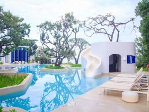 una piscina en un complejo con agua azul y árboles en Chelona Hua Hin, en Khao Tao