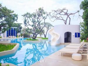 a pool at a resort with blue water and trees at Chelona Hua Hin in Khao Tao