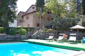 a house with a swimming pool with chairs and an umbrella at Agriturismo Borgo Del Senatore in Anghiari