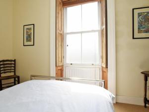 a bedroom with a white bed and a window at Riverbank Cottage in Alnwick