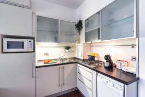 uma cozinha com armários brancos, um lavatório e um micro-ondas em [DUOMO-Cadorna] Cozy with WiFi & A/C em Milão