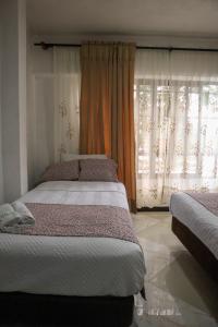 a bedroom with two beds and a window with curtains at Hotel Los Almendros in Santa María