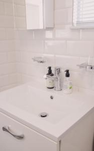 ein weißes Badezimmer mit einem Waschbecken und einer weißen Badewanne in der Unterkunft Brookwood Cottage in Somerset West