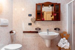 bagno con lavandino, servizi igienici e specchio di Residence Stella a Folgaria