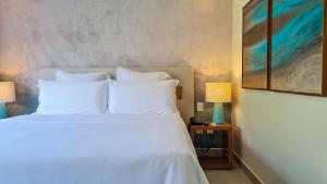 - une chambre dotée d'un lit avec des oreillers blancs et un tableau dans l'établissement Qavi - Suíte luxuosa na rua principal #ÎledePipa, à Pipa