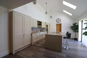 a kitchen with white cabinets and a table and a stool at Northumberland Luxury Stays - The Newland in West Chevington