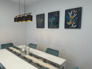 a dining room with a white table and four pictures on the wall at Apartment Wesseling in Wesseling