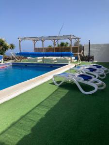 una piscina con un montón de sillas en la hierba en Finca Toredo, en San Miguel de Abona