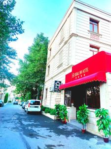 a building with a red awning next to a street at Sebail Inn Hotel in Baku