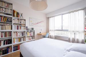 ein Schlafzimmer mit einem Bett und Bücherregalen mit Büchern in der Unterkunft Veeve - Scenes of the Eiffel Tower in Paris
