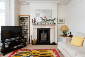a living room with a fireplace and a television at Veeve - Kew Grass House in Kew