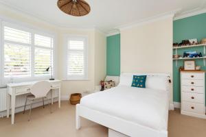 a bedroom with a white bed and a desk at Veeve - Kew Grass House in Kew