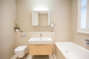 a bathroom with a sink and a toilet and a mirror at Veeve - Kew Grass House in Kew +13 photos