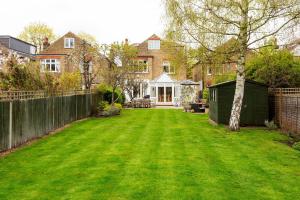 a yard with green grass and a fence at Veeve - Kew Grass House in Kew