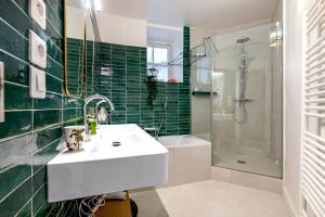 a bathroom with a sink and a shower with green tiles at Veeve - The Hopeful Romantic in Paris
