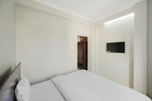 a white bedroom with a bed and a television at Goroomgo Grace Premium Bhubaneswar in Bhubaneshwar