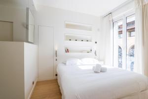 a white bedroom with a bed and a window at Veeve - Alabaster Bright in Paris