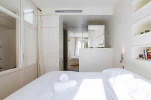 a white bedroom with a bed and a mirror at Veeve - Alabaster Bright in Paris