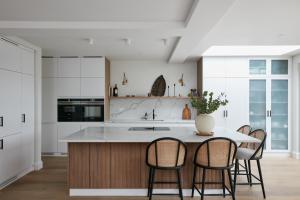 a kitchen with white cabinets and a table with chairs at Veeve - Pine Reflections in London
