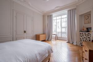 ein weißes Schlafzimmer mit einem Bett und einem großen Fenster in der Unterkunft Veeve - A Window to Paris in Paris