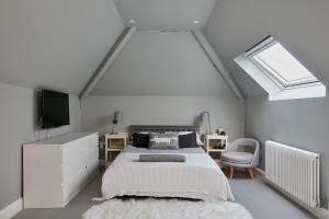 a white bedroom with a bed and a skylight at Veeve - Pine Reflections in London
