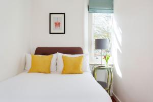 a bedroom with a bed with yellow pillows and a window at Veeve - Explorer's Escape in London