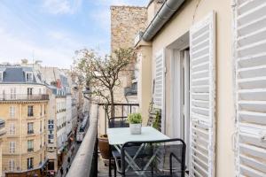 a table on a balcony with a view of a city at Veeve - Loft Living on Luxembourg in Paris