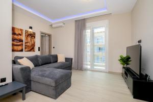 a living room with a gray couch and a tv at Alexandra's comfort by homebrain in Alexandroupoli