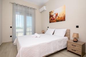 a bedroom with a large white bed and a window at Alexandra's comfort by homebrain in Alexandroupoli